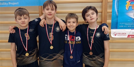 Powiększ grafikę: 4 chłopców pozujących do zdjęcia z medalami na szyi na sali gimnastycznej